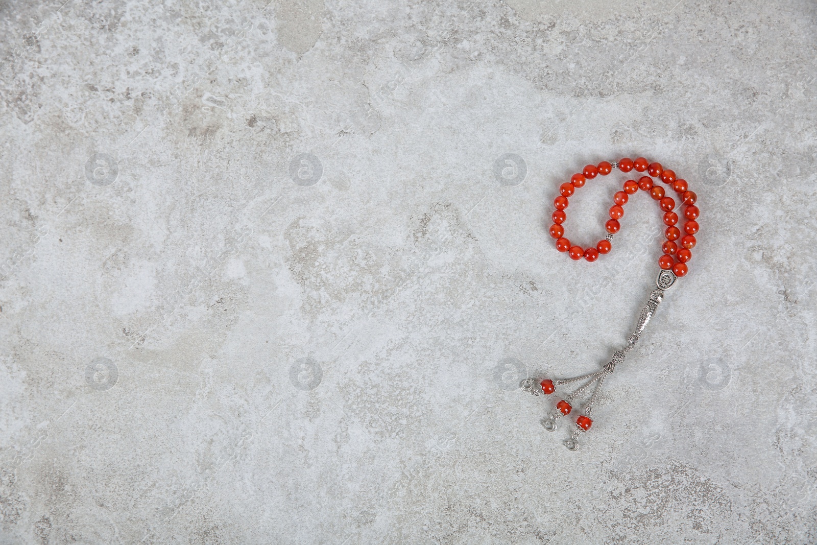 Photo of Muslim prayer beads and space for text on grey background, top view