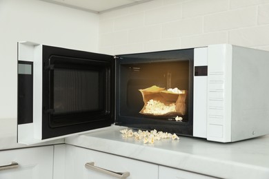 Photo of Open microwave oven with fresh popcorn on countertop in kitchen