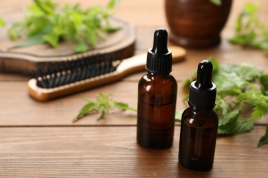 Stinging nettle extract in bottles on wooden table, closeup with space for text. Natural hair care