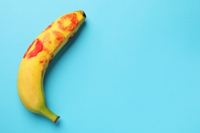 Photo of Banana with red lipstick marks on light blue background, top view with space for text. Sex concept