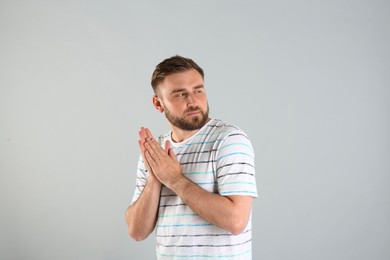 Photo of Greedy young man rubbing hands on light grey background