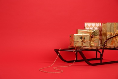 Photo of Sleigh with gift boxes on red background. Space for text