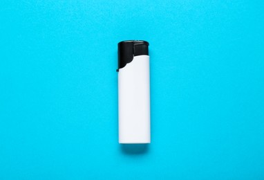 Photo of White plastic cigarette lighter on light blue background, top view