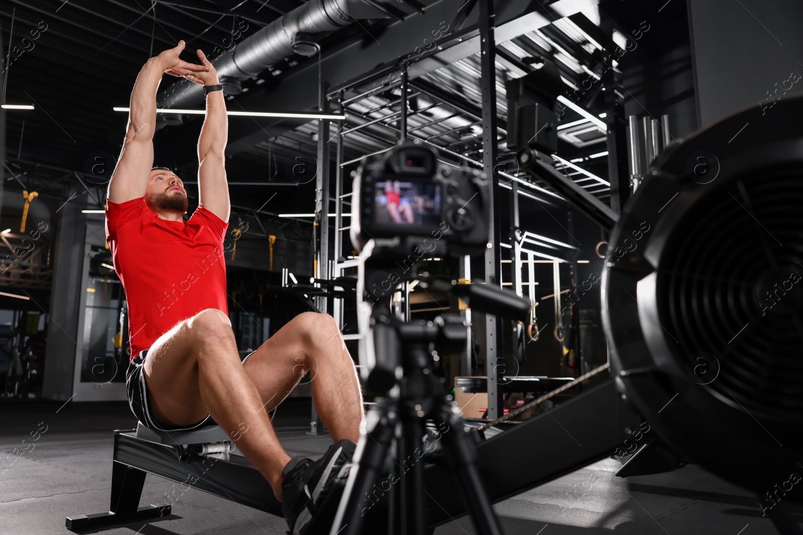 Photo of Man recording workout on camera at gym. Online fitness trainer