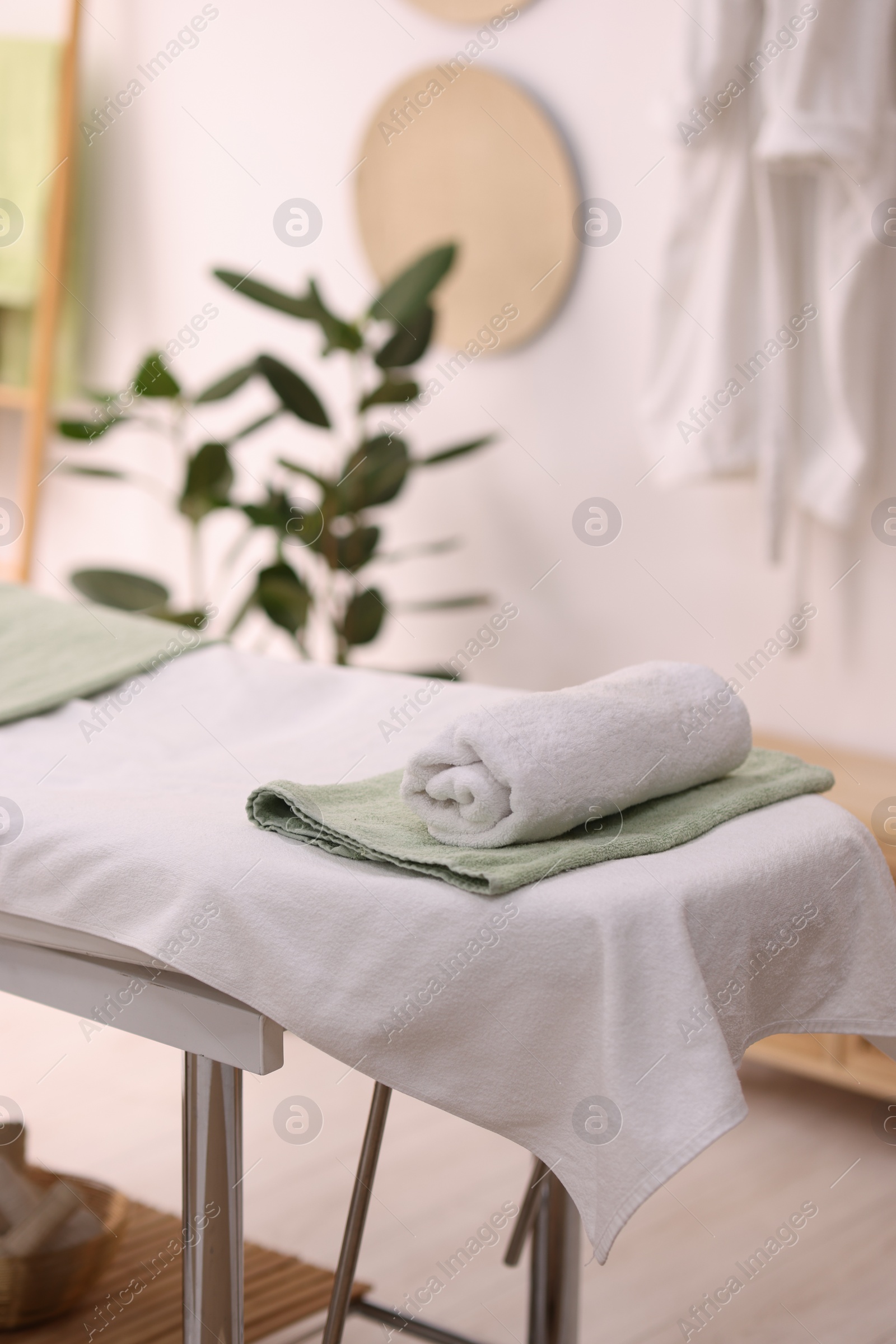 Photo of Comfortable massage table with clean towels in spa center