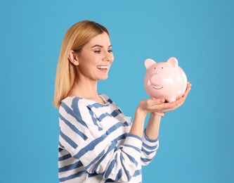 Woman with piggy bank on color background