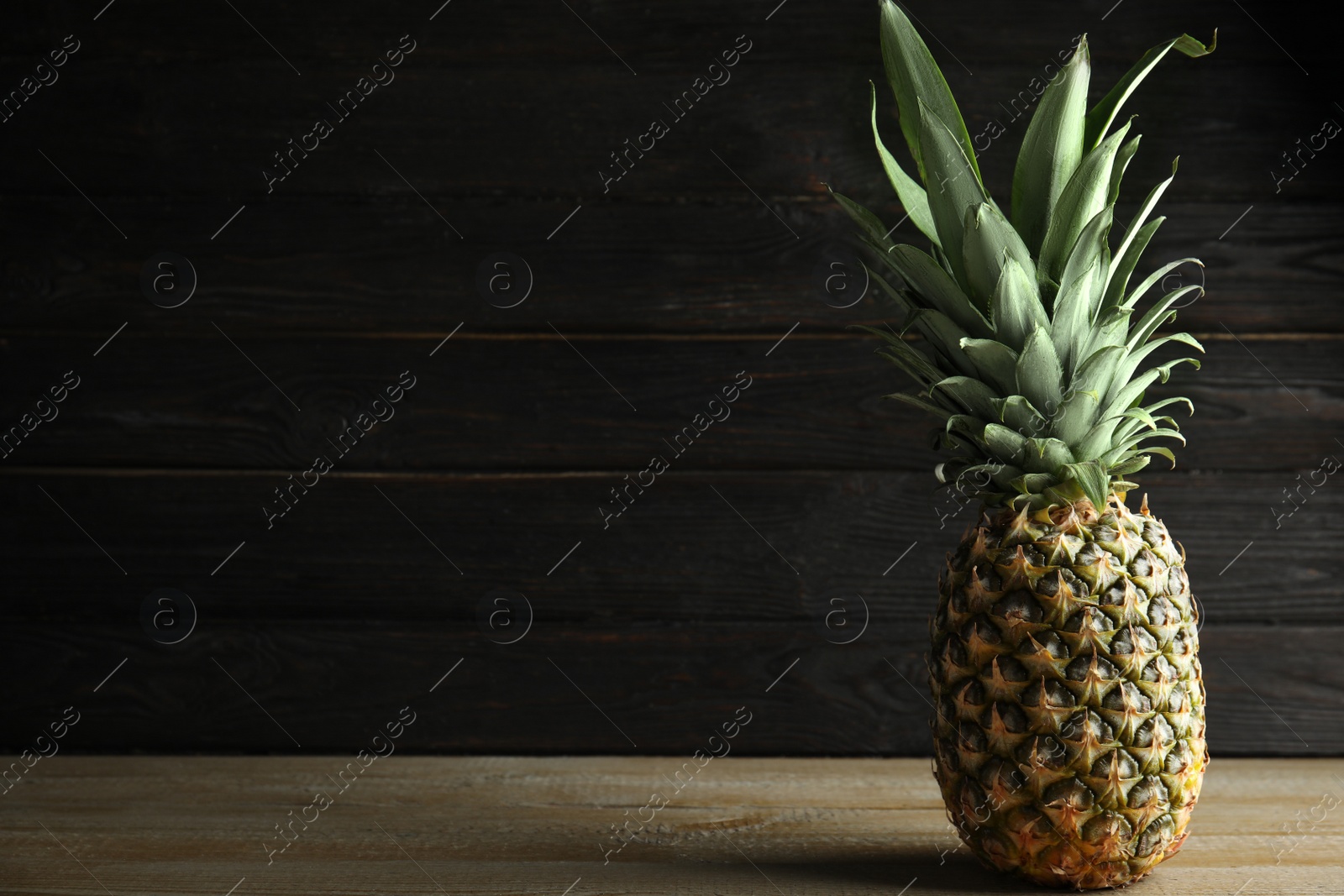 Photo of Fresh ripe juicy pineapple on wooden table. Space for text