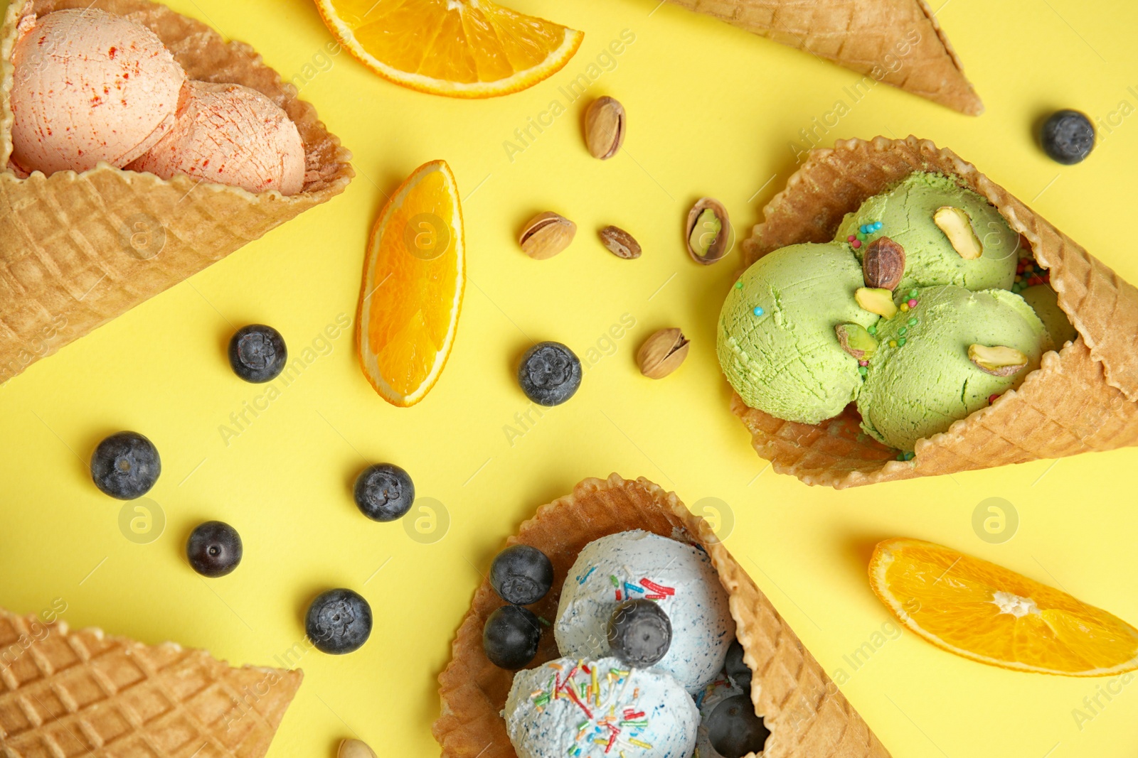 Photo of Flat lay composition with delicious ice creams in waffle cones on color background