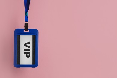 Photo of Plastic vip badge hanging on pale pink background, space for text