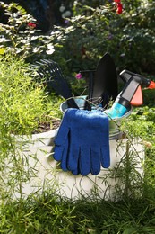 Photo of Wooden crate with gardening gloves, tools and potted plant on grass outdoors