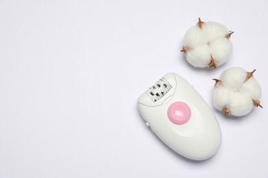 Modern epilator and fluffy cotton flowers on white background, top view