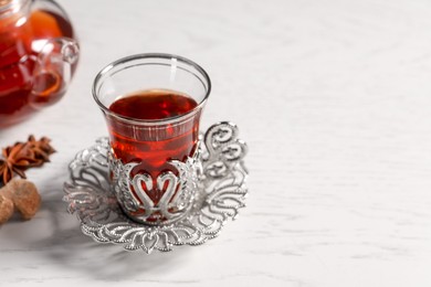 Photo of Glass of traditional Turkish tea in vintage holder on white table, closeup. Space for text