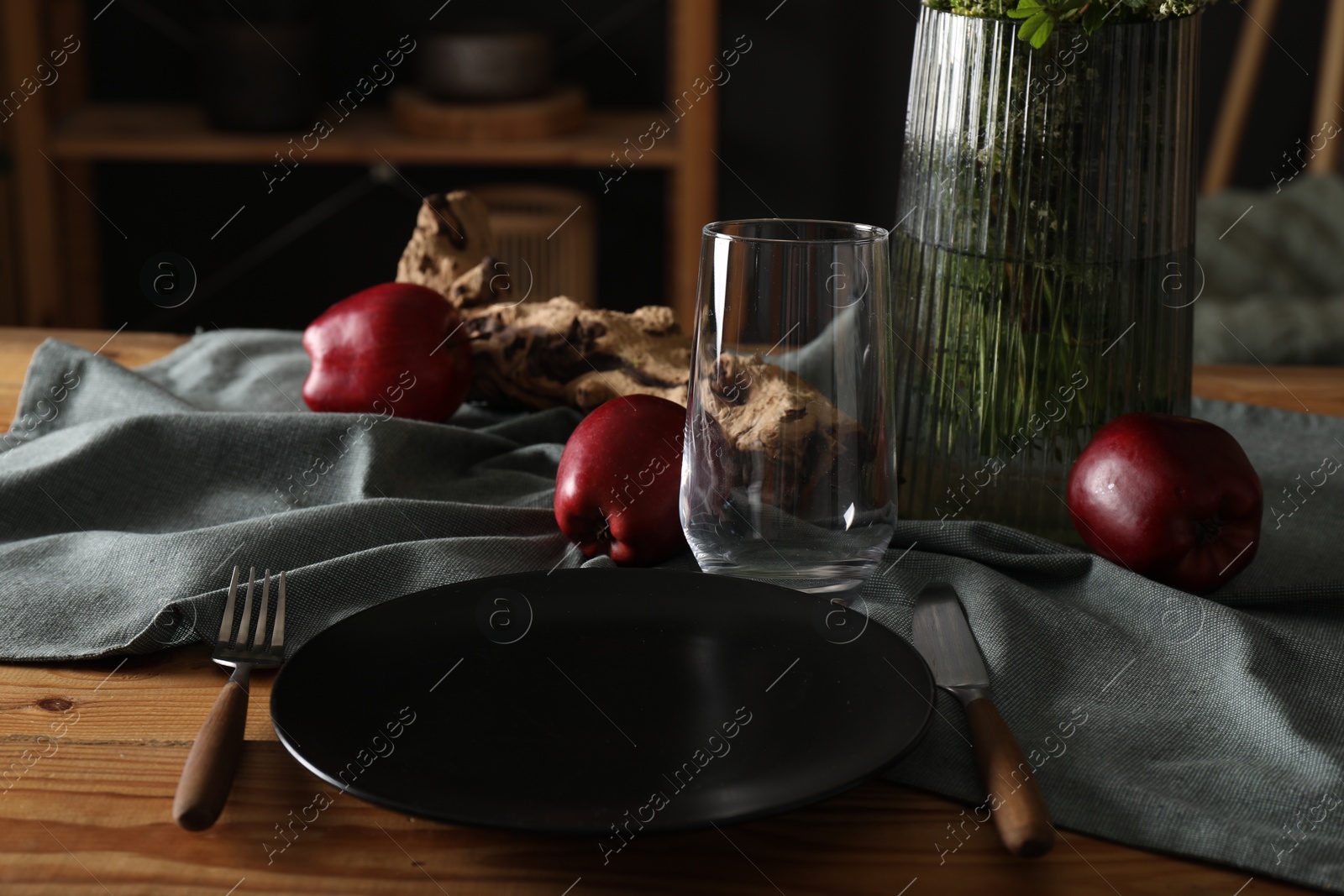 Photo of Set of clean dishware, ripe red apples and flowers on dining table indoors