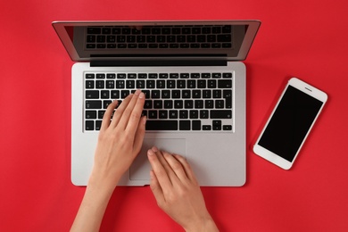 Photo of Woman using modern laptop at color table, top view