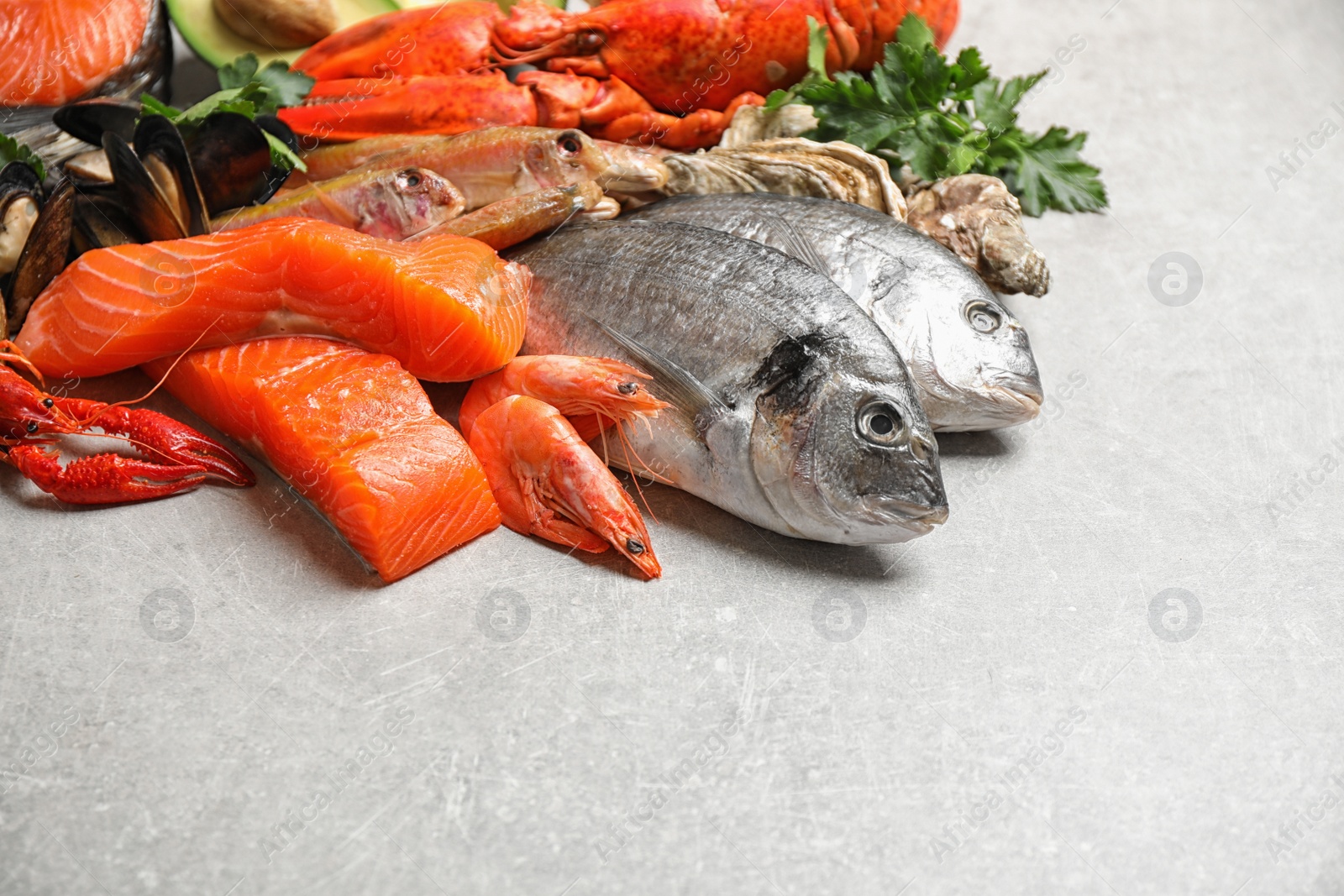 Photo of Fresh raw fish and different seafood on light grey table