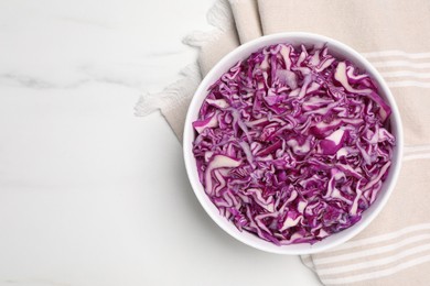 Photo of Bowl with shredded red cabbage on white marble table, top view. Space for text