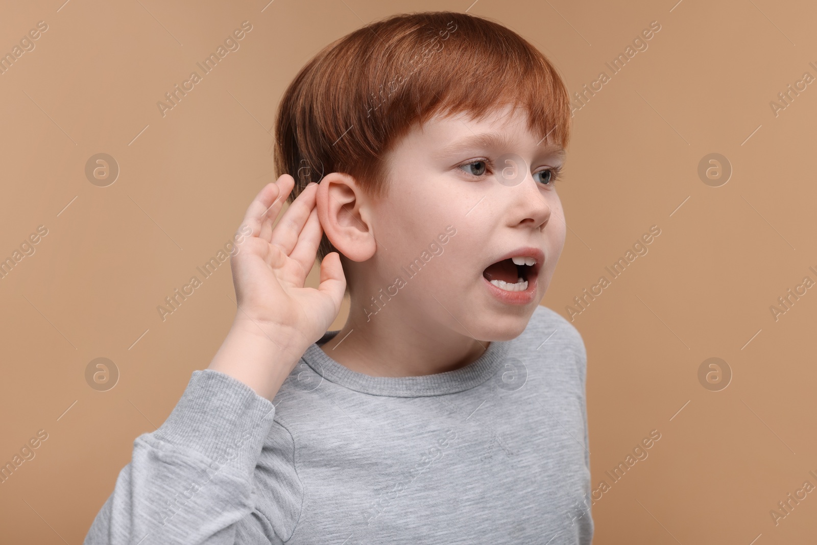 Photo of Little boy with hearing problem on pale brown background