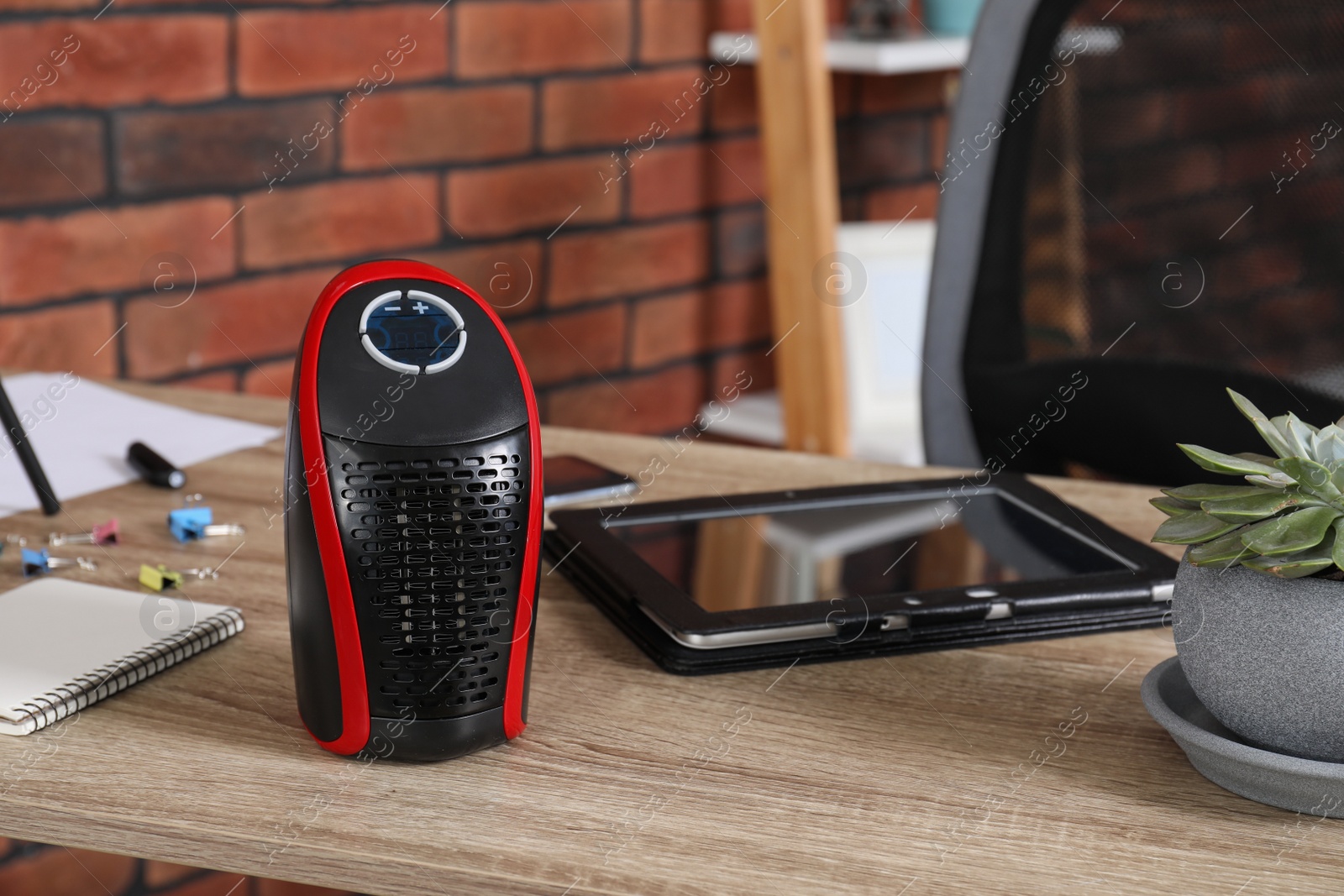 Photo of Compact electric heater on wooden table indoors, closeup