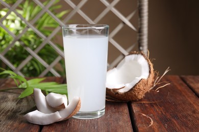 Photo of Glass of coconut water, leaf and nuts on wooden table