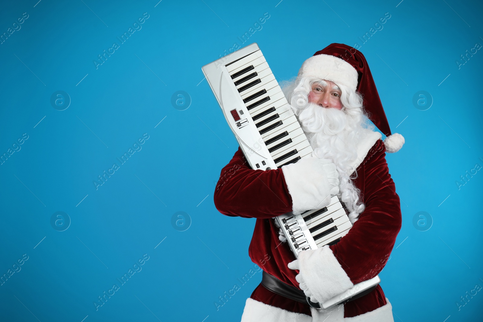 Photo of Santa Claus with synthesizer on blue background, space for text. Christmas music