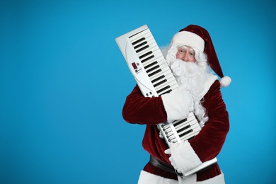 Photo of Santa Claus with synthesizer on blue background, space for text. Christmas music