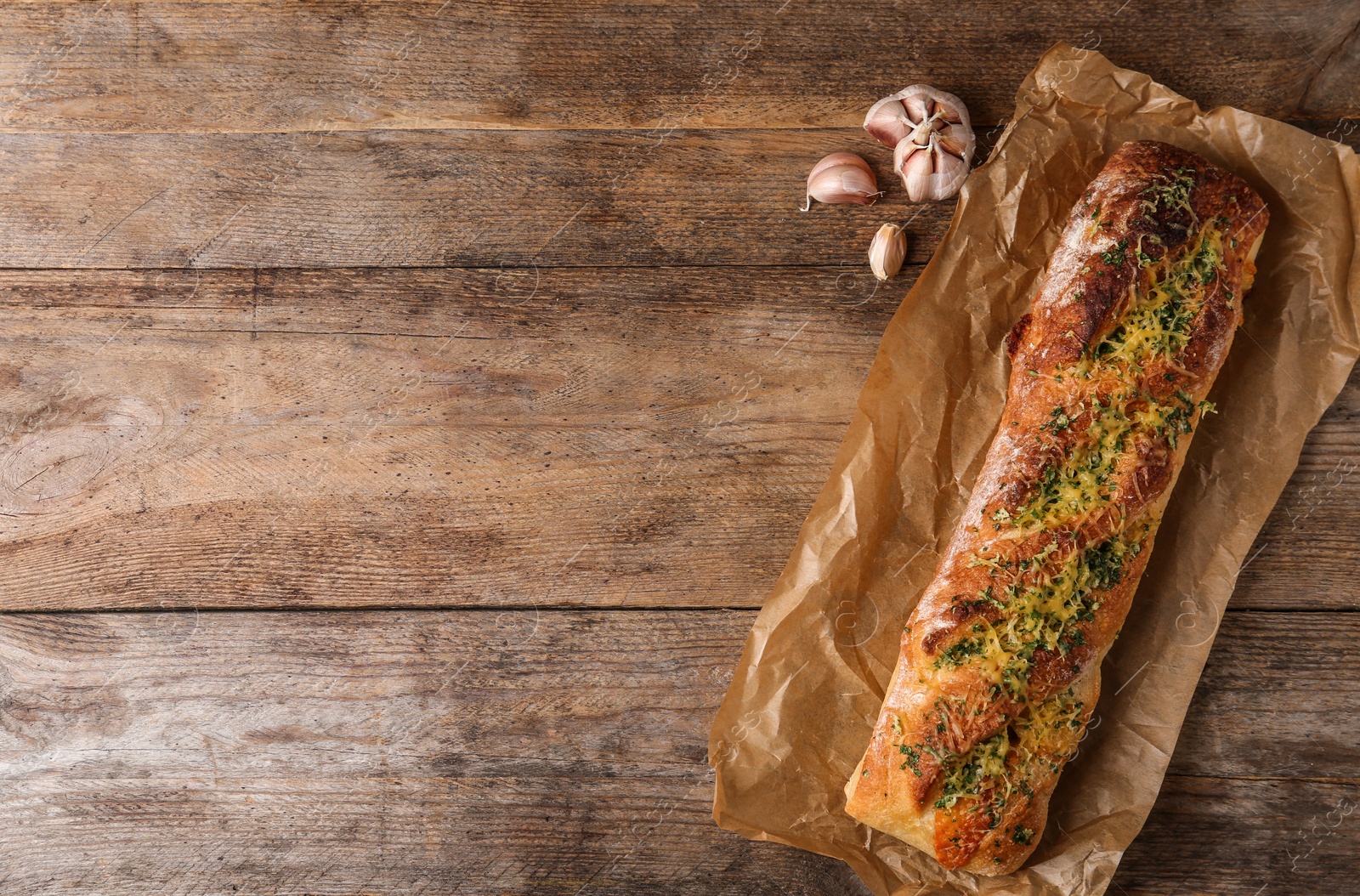 Photo of Tasty homemade garlic bread with cheese and herbs on wooden table, flat lay. Space for text