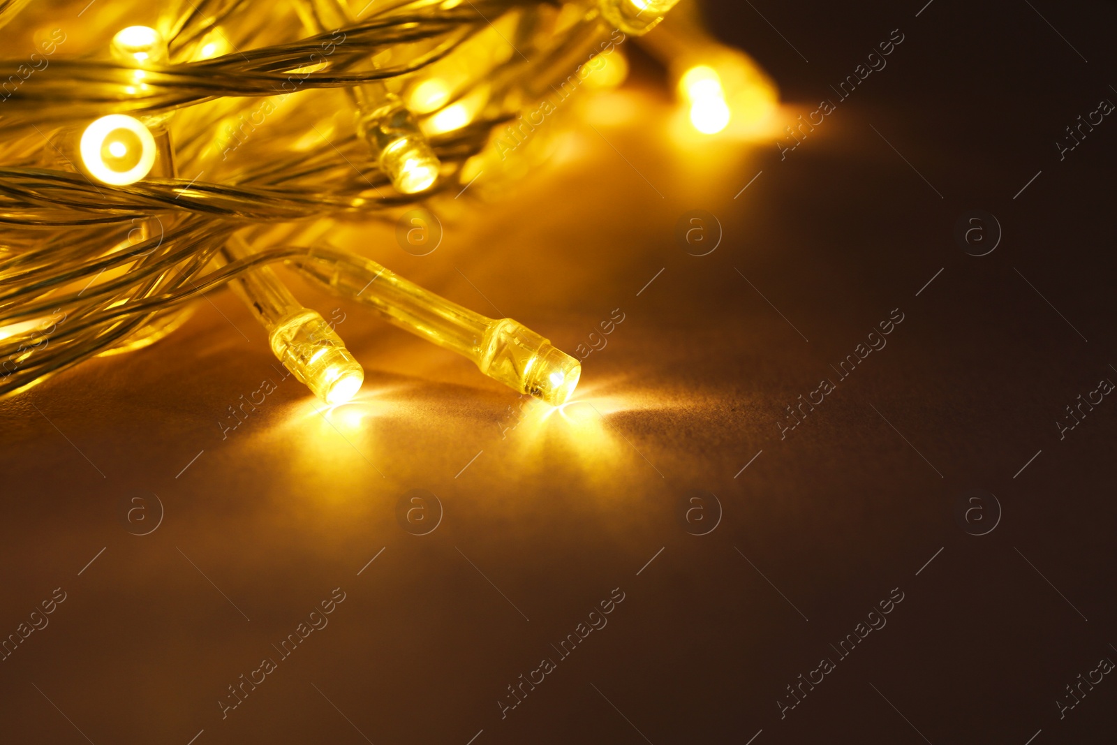 Photo of Glowing Christmas lights on violet background, closeup