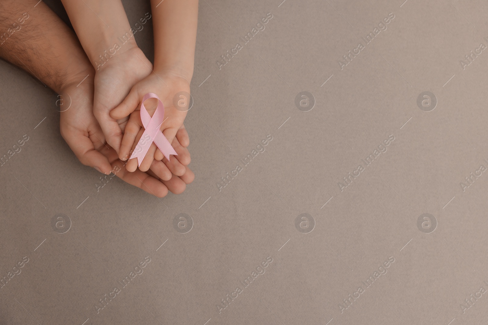 Photo of Family holding pink ribbon on grey background, top view with space for text. Breast cancer awareness