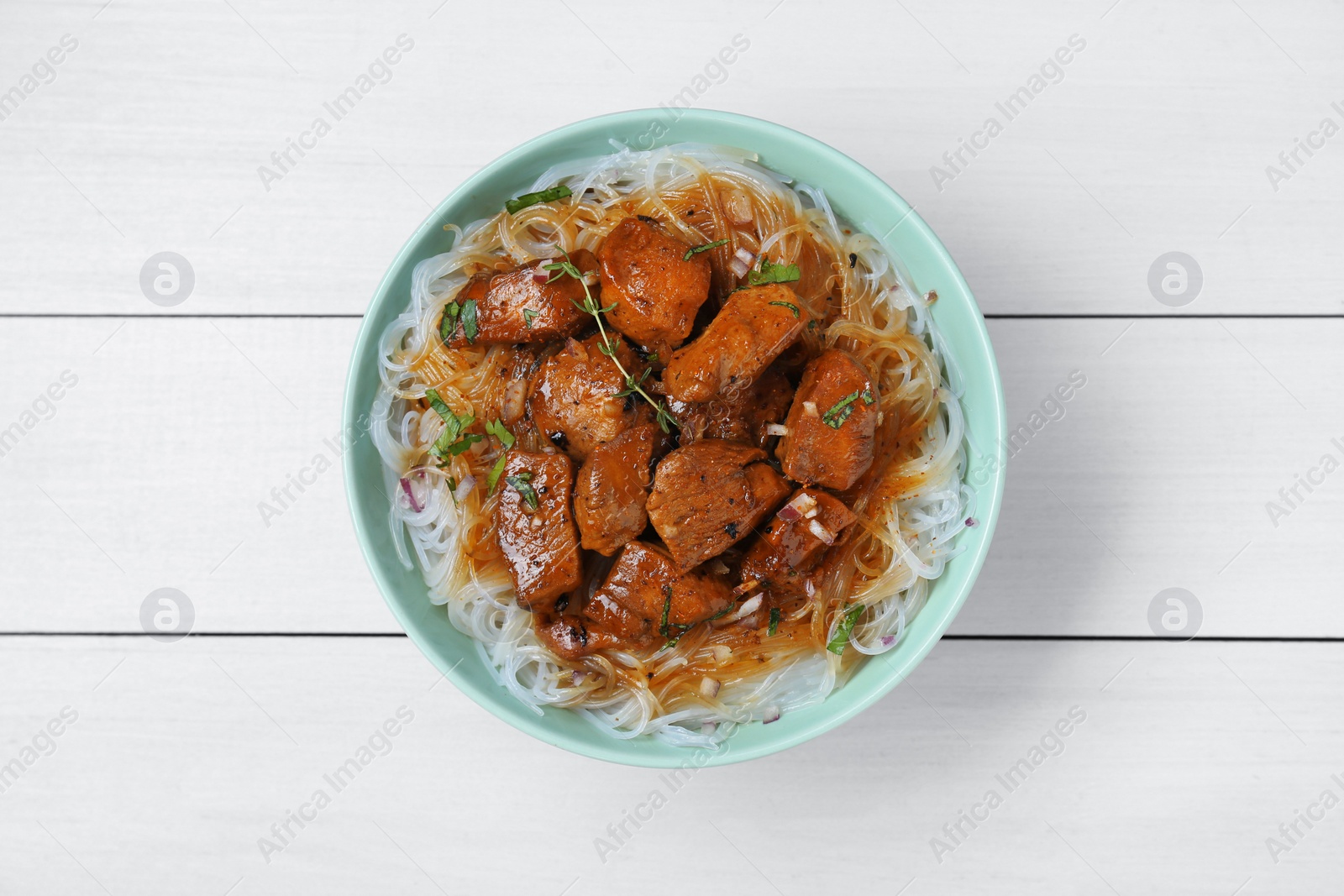 Photo of Bowl with pieces of soy sauce chicken and noodle on white wooden table, top view