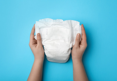 Photo of Woman with diaper on light blue background, closeup