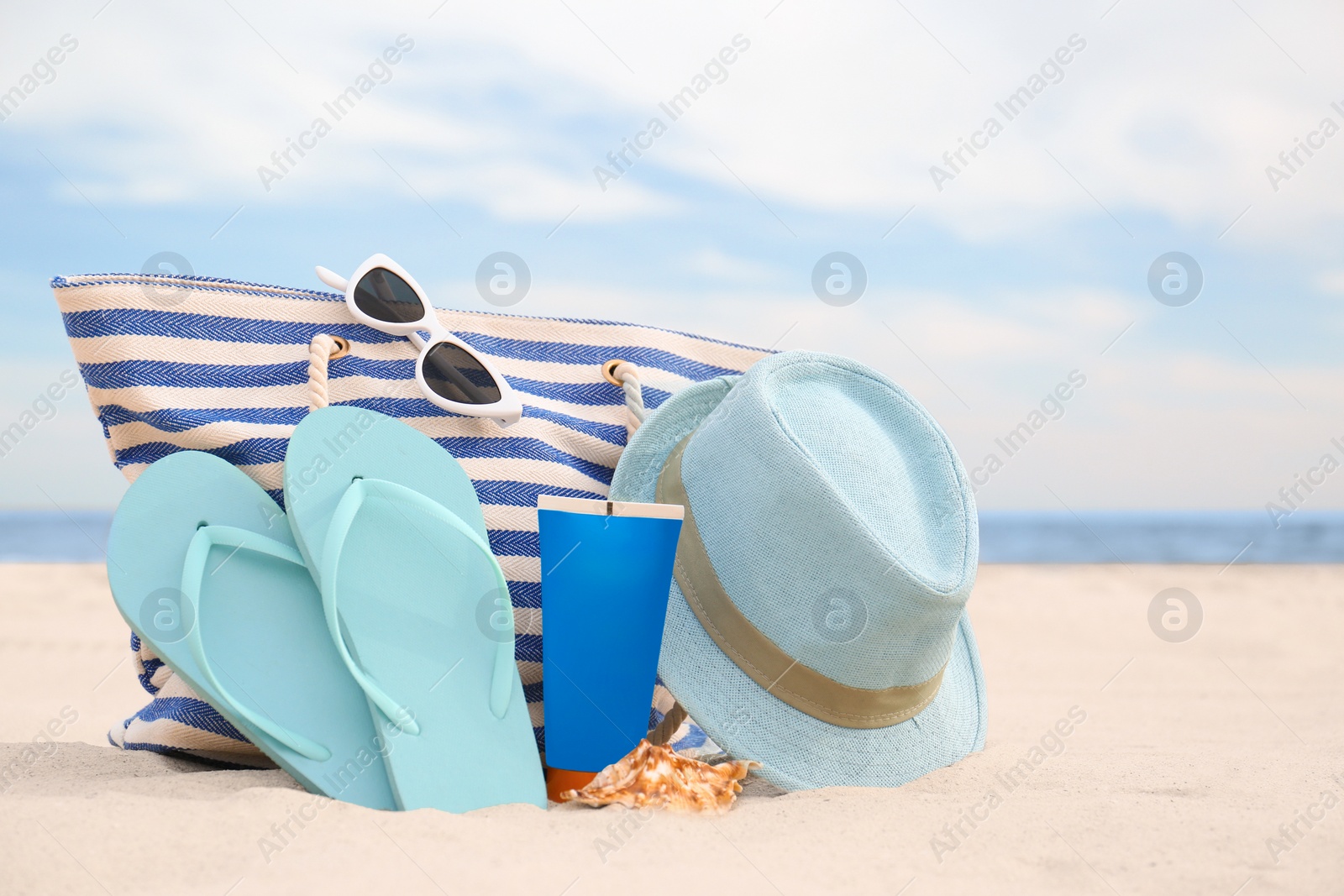 Photo of Different stylish beach objects on sand near sea