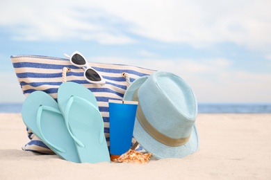 Different stylish beach objects on sand near sea