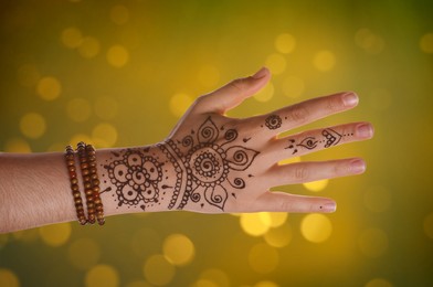 Image of Woman with henna tattoo on hand against blurred lights, bokeh effect