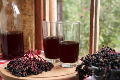 Photo of Elderberry drink and Sambucus berries on wooden table near window