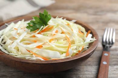 Photo of Fresh cabbage salad served on wooden table, closeup