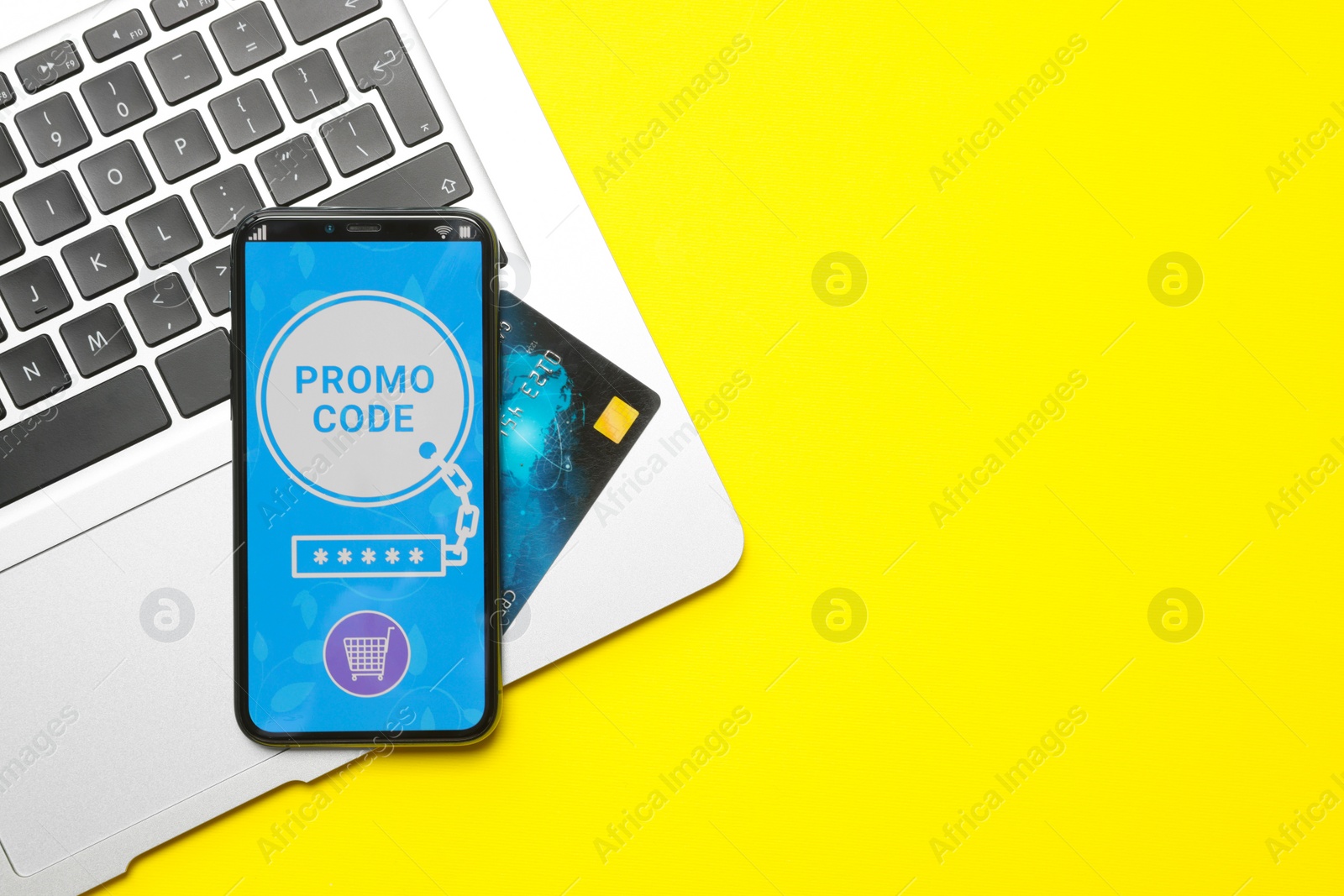 Photo of Smartphone with activated promo code, credit card and laptop on yellow background, flat lay. Space for text