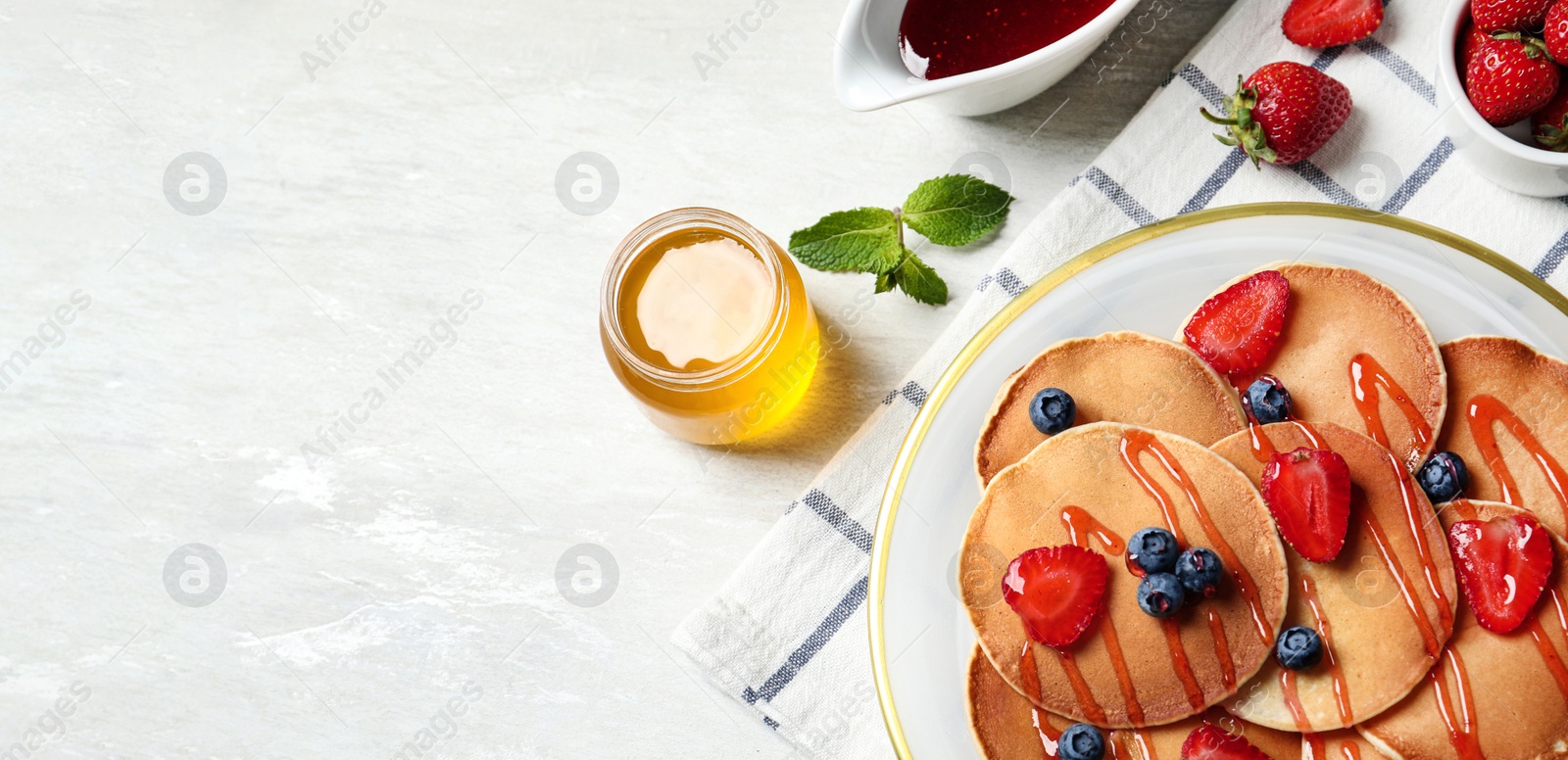 Image of Tasty pancakes with berries served on light table, flat lay with space for text. Banner design