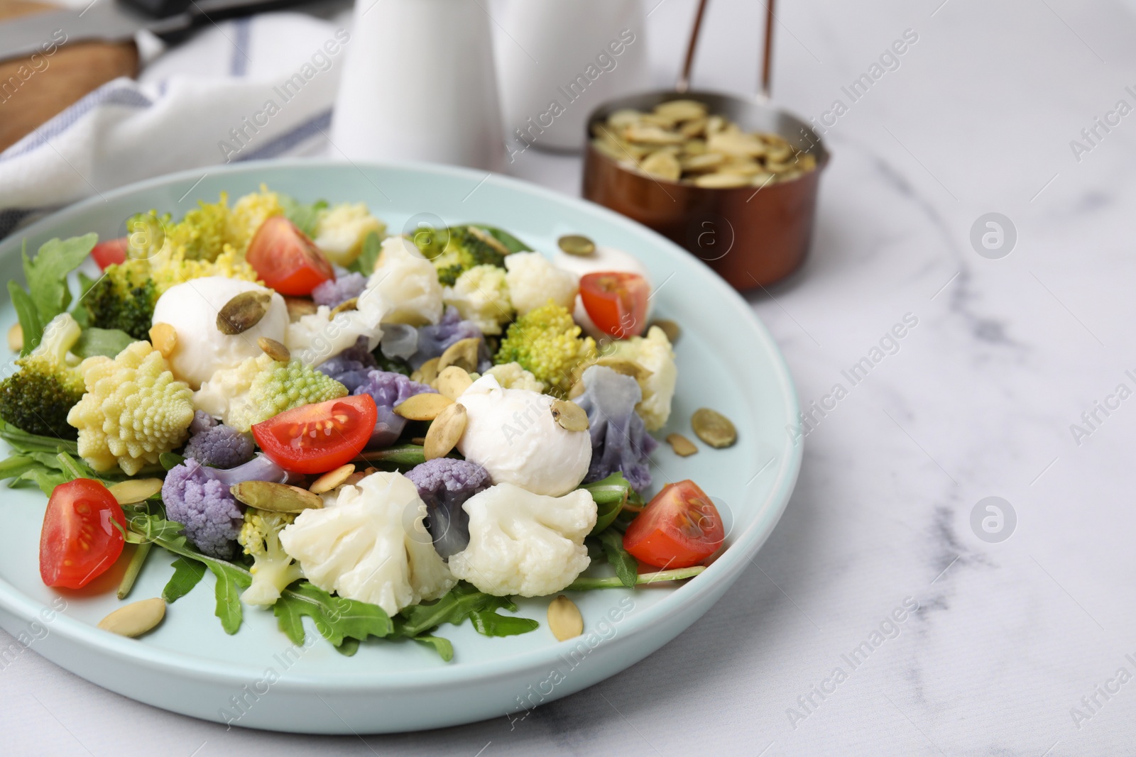 Photo of Delicious salad with cauliflower, tomato and cheese served on white marble table. Space for text