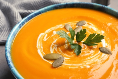 Photo of Bowl with tasty pumpkin soup on table, closeup