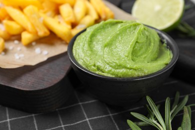 Photo of French fries, lime, rosemary and avocado dip on serving board, closeup