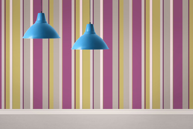 Image of Stylish pendant lamps hanging near striped wall in room