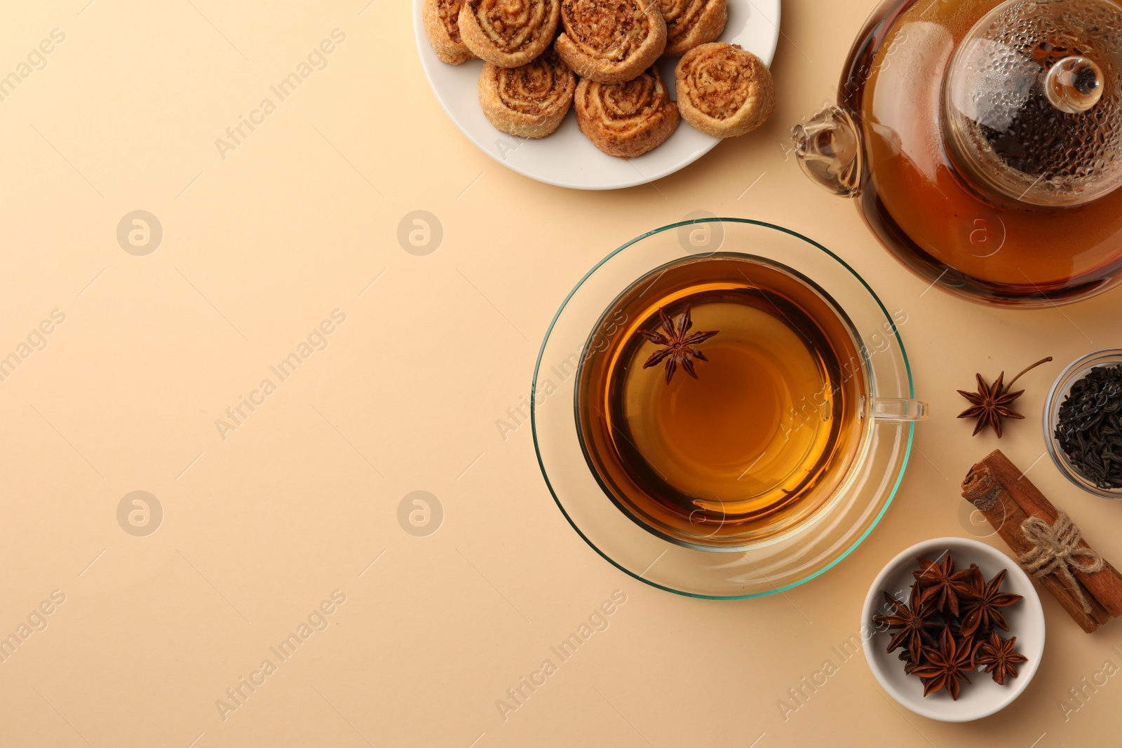 Photo of Flat lay composition with aromatic tea, cookies and anise stars on beige table. Space for text