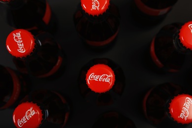 Photo of MYKOLAIV, UKRAINE - NOVEMBER 14, 2018: Bottles of Coca-Cola on black background, top view