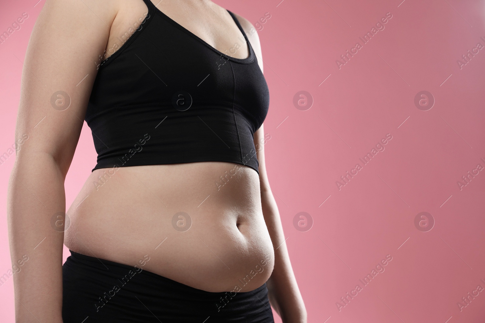 Photo of Woman with excessive belly fat on pink background, closeup. Overweight problem