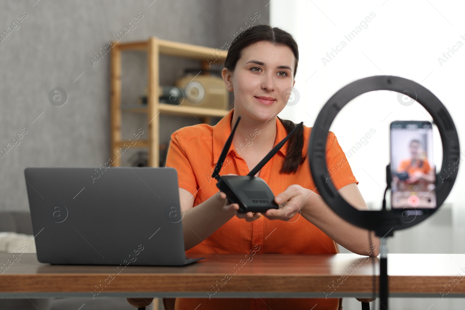 Photo of Technology blogger showing WI-FI router while recording video at home