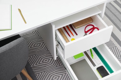 Office supplies in open desk drawers indoors