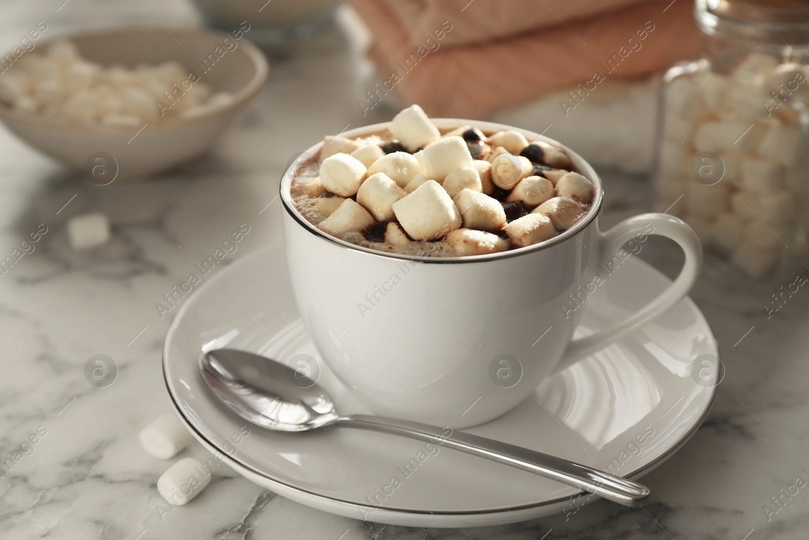 Photo of Cup of aromatic hot chocolate with marshmallows served on light marble table, closeup