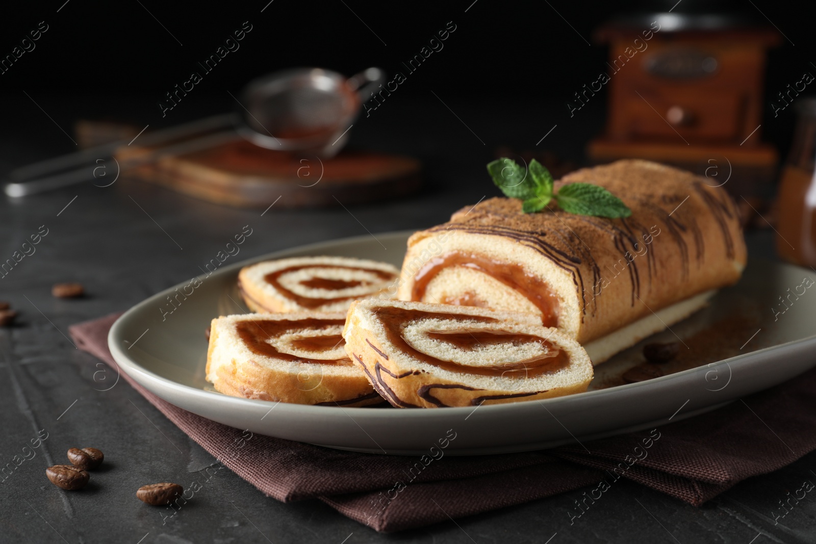 Photo of Tasty cake roll with jam and mint on grey table