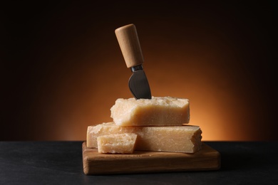 Delicious parmesan cheese with knife on black table