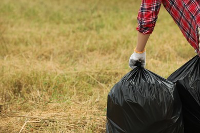 Photo of Woman with trash bags full of garbage outdoors, closeup. Space for text